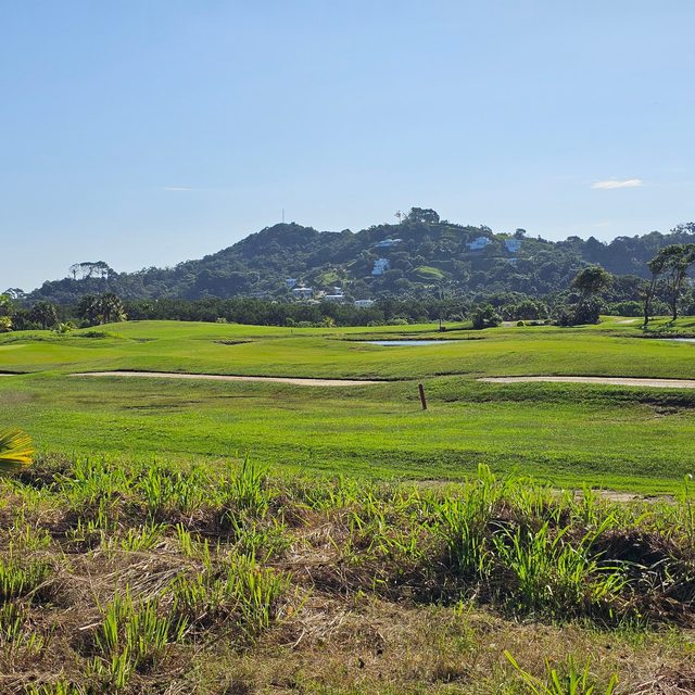 Long bunkers crossing the fairway, a green hill dotted with houses behind