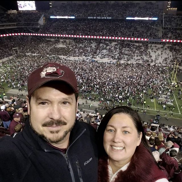 Gunny and Nikki in the stands at Kyle Field as fans fill the field after a game