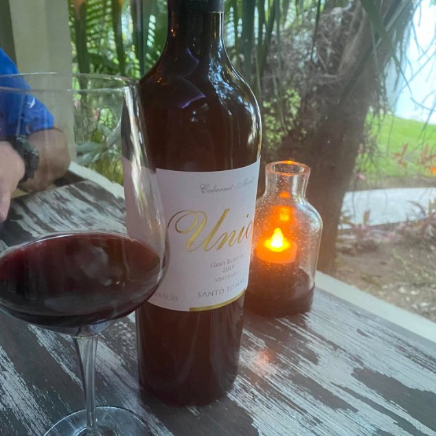 A bottle of Mexican red wine and a glass on a candlelit table