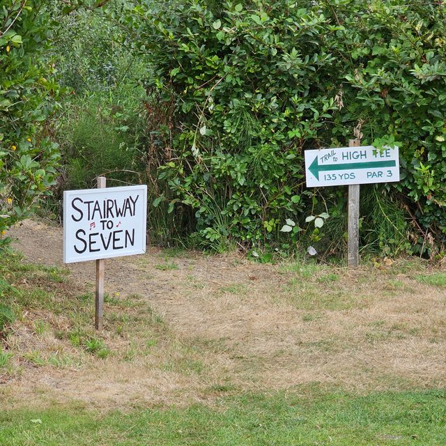 Hand-painted signs reading Stairway to Seven and Trail to High Tee, 135 yards, par 3
