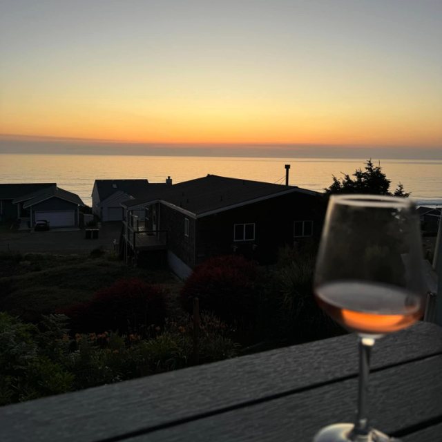 A glass of rosé on the rental deck, with the sun setting over the Pacific
