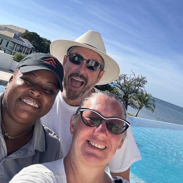 Sheree, Gunny, and Nikki smiling in a selfie by the infinity pool