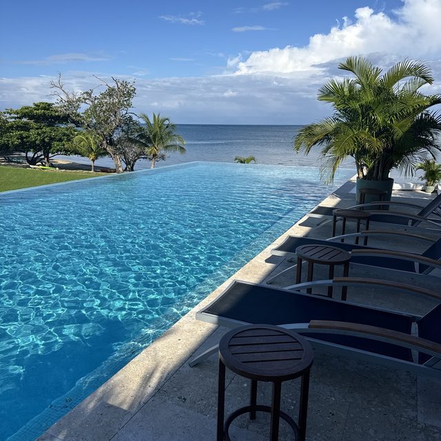 Loungers lined up along the infinity pool edge facing the Caribbean