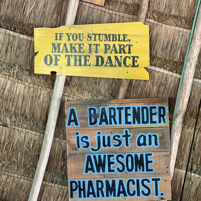 Hand-painted beach bar signs on a thatched wall