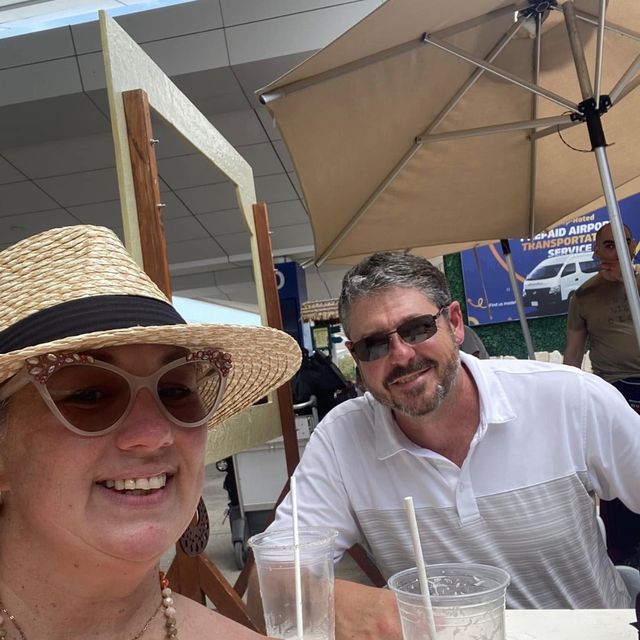 Nikki in a straw hat and Gunny in sunglasses at an outdoor table