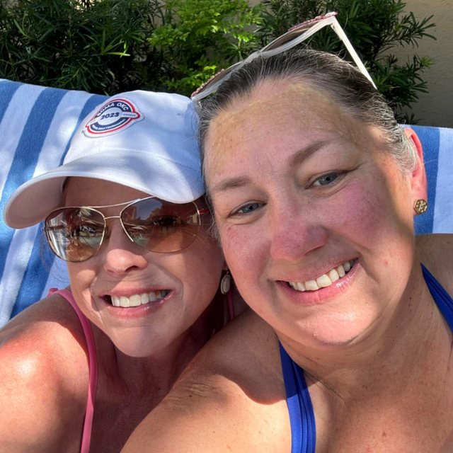 Nikki and a friend smiling together poolside