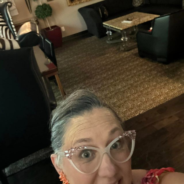 Nikki's selfie in front of the suite's living room, with a gilded mirror and black leather sofa